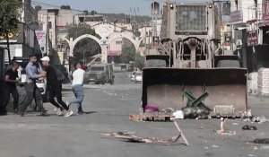 Des Palestiniens jettent des pierres sur un bulldozer israélien lors d'un raid