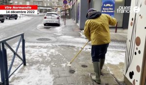 Les commerçants enlèvent la neige des trottoirs à Vire Normandie.