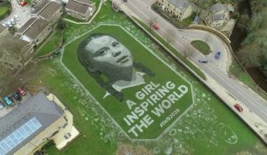 Un artiste peint le portrait géant de Greta Thunberg sur un terrain d'école