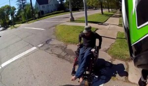 Un motard aide un homme en fauteuil roulant