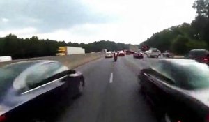 Un motard à fond entre les voitures sur l'autoroute