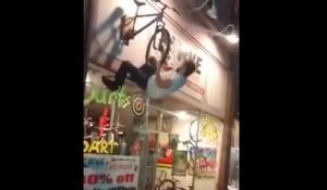 Un homme ivre s'accroche a l'enseigne d'un magasin de vélo