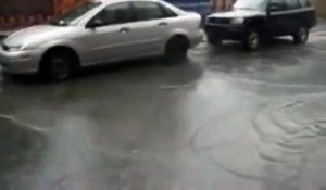 Une bouche d'égout explose en dessous d'une voiture