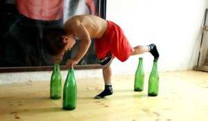 Un petit garçon de 5 ans fait des pompes sur des bouteilles de verre