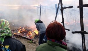 Démantèlement de la jungle de Calais, les migrants éteignent un feu de cabane