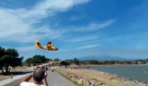 Un canadair frôle des passants au moment de recharger en eau dans un lac