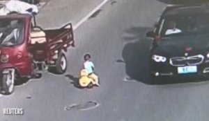 Un enfant en trotteur au milieu des voitures
