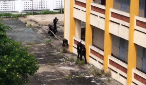 La police vietnamienne escalade un immeuble avec une perche