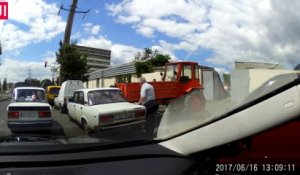 Ce russe essaie de retenir un tracteur sans frein et se retrouve coincé contre une voiture