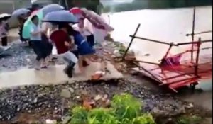 Cette femme traverse un pont sur le point d'etre emporté en pleine inondation