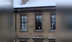 Cette vielle jette des boules de neige par la fenêtre sur les gens !