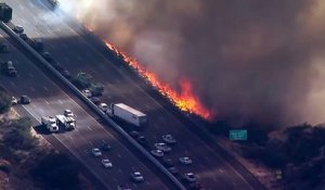 Un hélicoptère largue de l'eau sur une autoroute au bord des flammes (Californie)