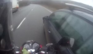 Une voiture double et tape dans une moto en la doublant dans sa voie