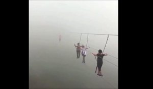Ces touristes traversent un pont suspendu perdu dans la brume... Impressionnant