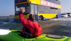 Faire du kayak sur une route inondée alors que des voitures roulent encore