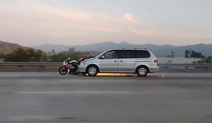 Une voiture roule en poussant une moto encastrée dans le par-chocs