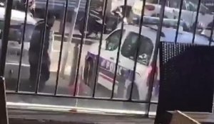Un homme détruit une voiture de police sous les yeux d'un policier