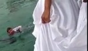 Une femme en robe de mariée saute dans l'eau