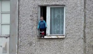 Un jeune enfant joue sur le bord d’une fenêtre au 8ème étage d’un immeuble