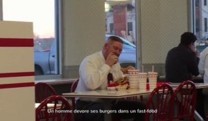 Un homme dévore ses burgers dans un fast-food
