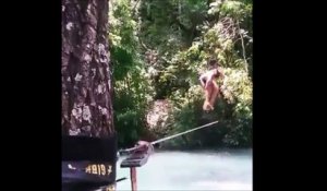 Une jolie fille en bikini fait des acrobaties sur une corde au dessus de l'eau