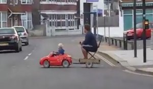 Au volant de sa mini-voiture, le petit garçon conduit son père à la maison