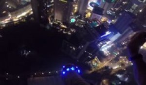 Un homme saute en parachute dans une piscine depuis un immeuble