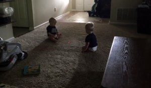 2 bébés jumeaux chassent un laser sur le tapis.. Trop mignon