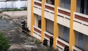 La police vietnamienne escalade un immeuble avec une perche