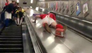 Un supporter de football descend un escalator en glissant.