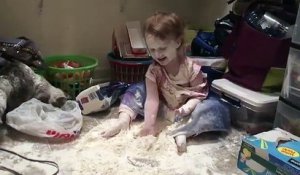 Une enfant et un chat jouent avec de la farine