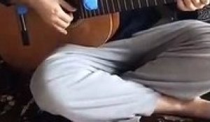 Il joue avec son bébé posé sur la guitare