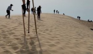 Julien grimpe la dune du Pilat sur ses échasses landaises