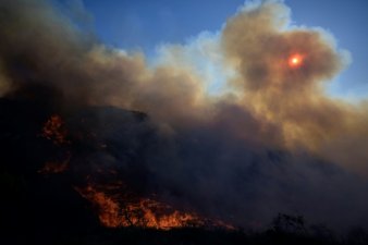 Un hélicoptère largue une cargaison d'eau sur un feu de forêt à Keratea, près d'Athènes, le 30 juin 2024 en Grèce