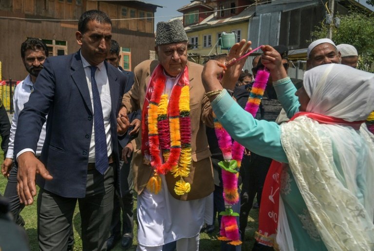 Un partisan de la Conférence Nationale porte une bannière avec des photos de dirigeants du parti lors d'un meeting de campagne électorale à Srinagar, la principale ville du Cachemire administrée par l'Inde, le 11 mai 2024